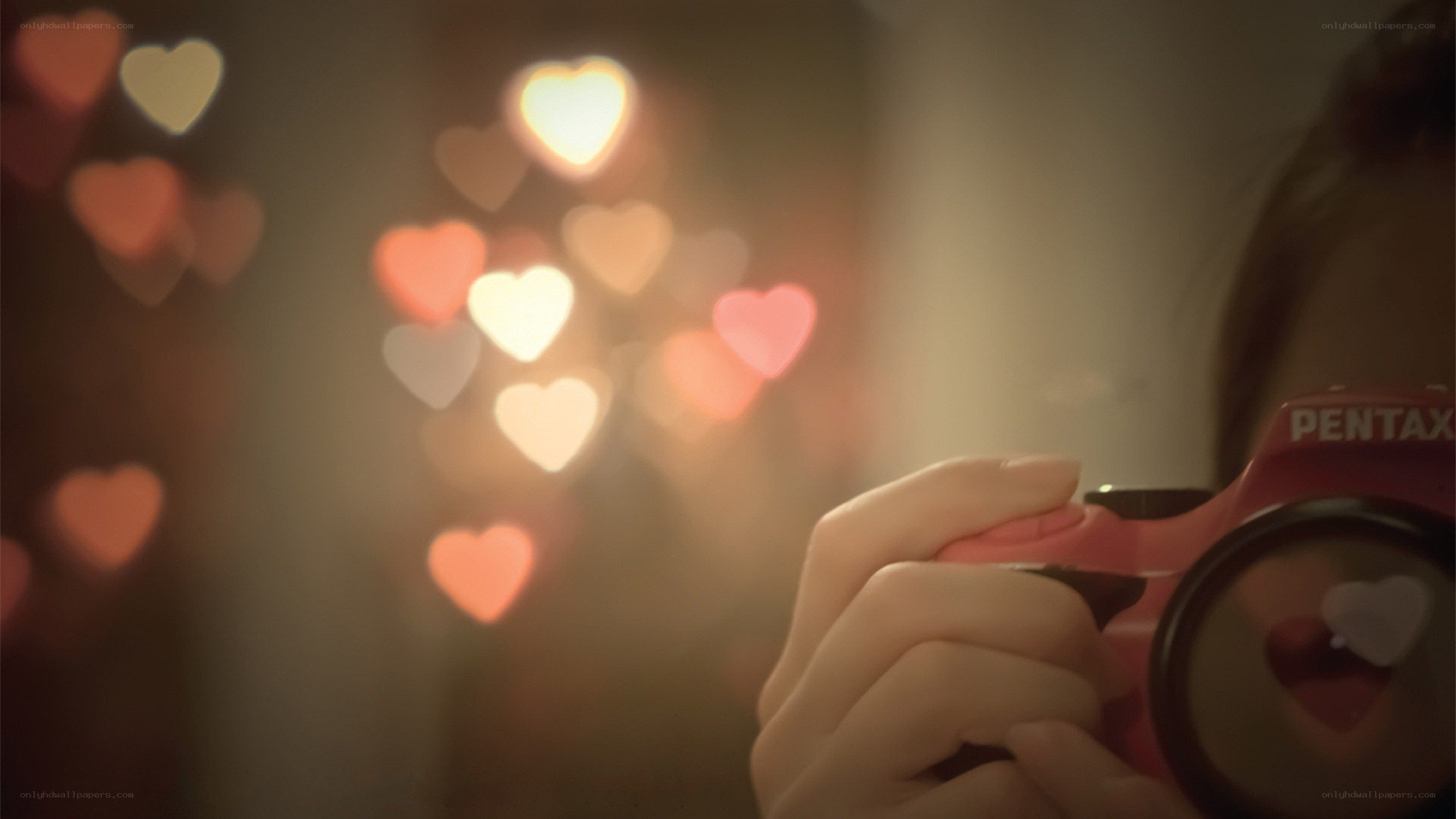 person holding camera with heart bokeh