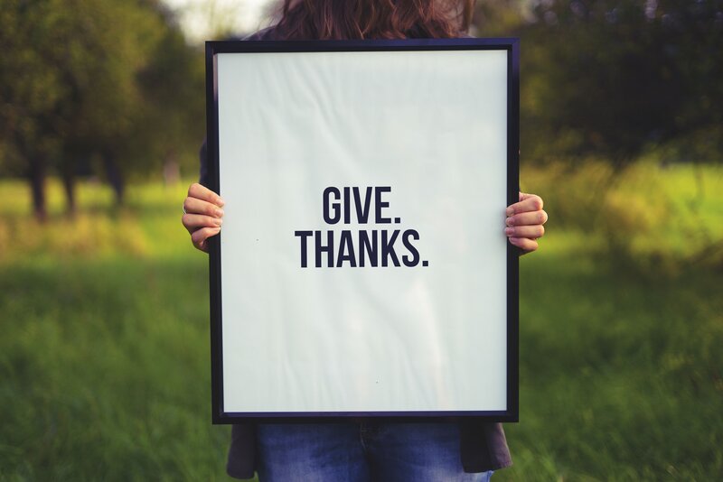 person holding give thanks sign