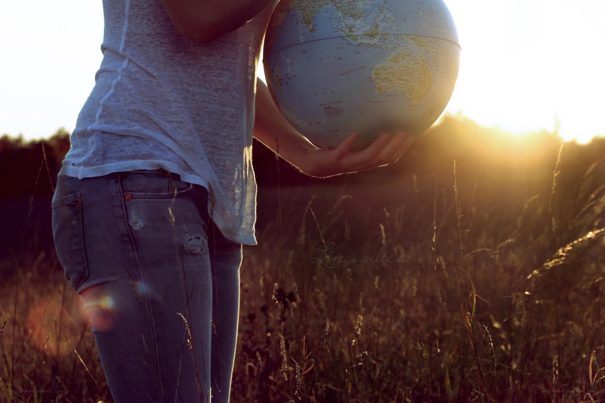 person holding globe at sunset