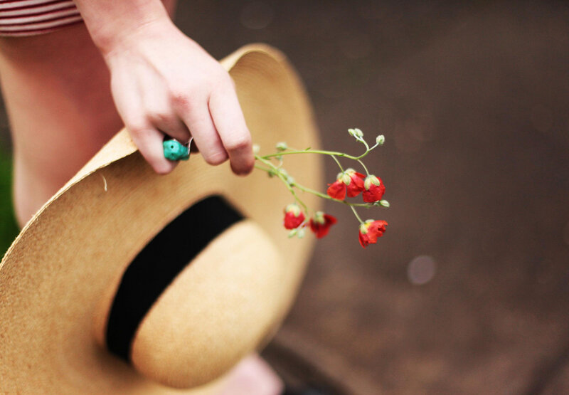 Person Holding Hat and Flowers