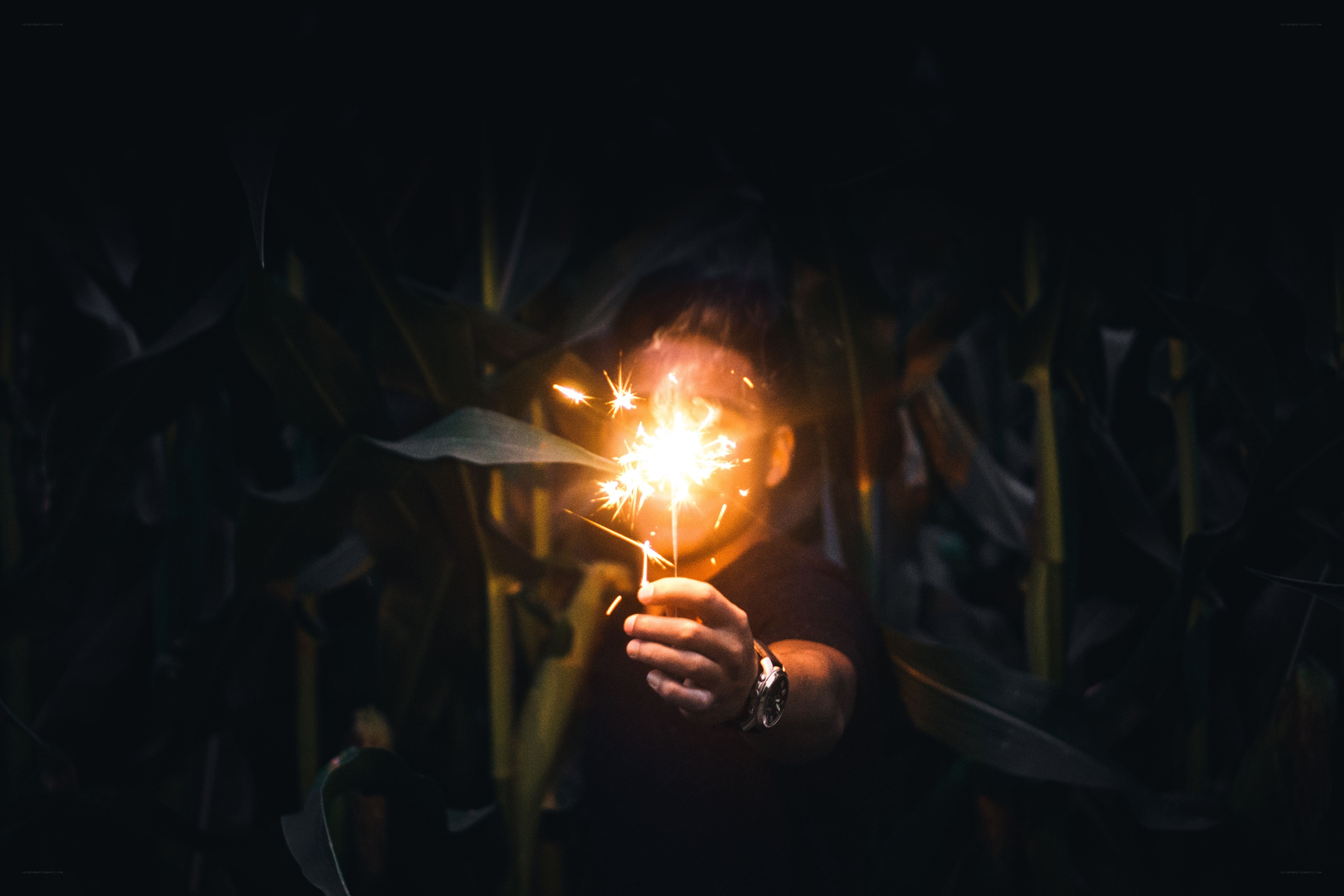 person holding sparkler in dark