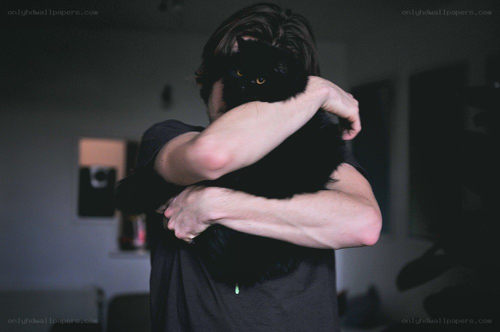 person hugging a black cat