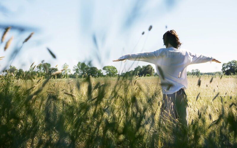 Person in a field with arms outstretched