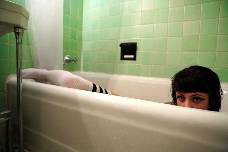 person in bathtub with green tiles