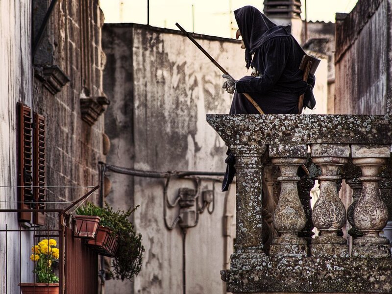 person in black hood on balcony