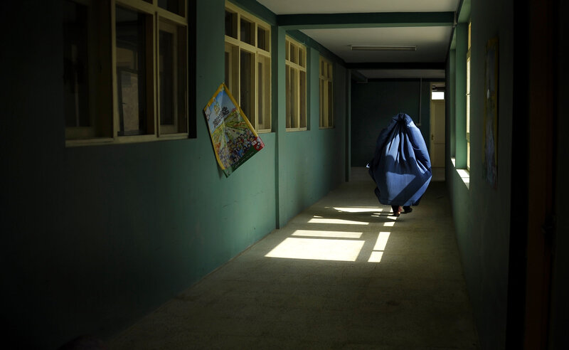 Person in blue cloak walking down hallway