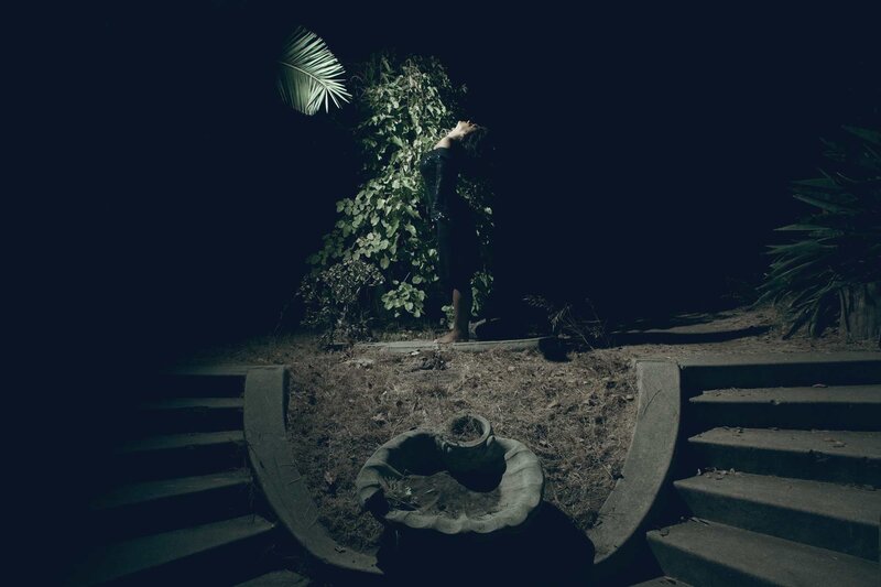 person in dark garden at night