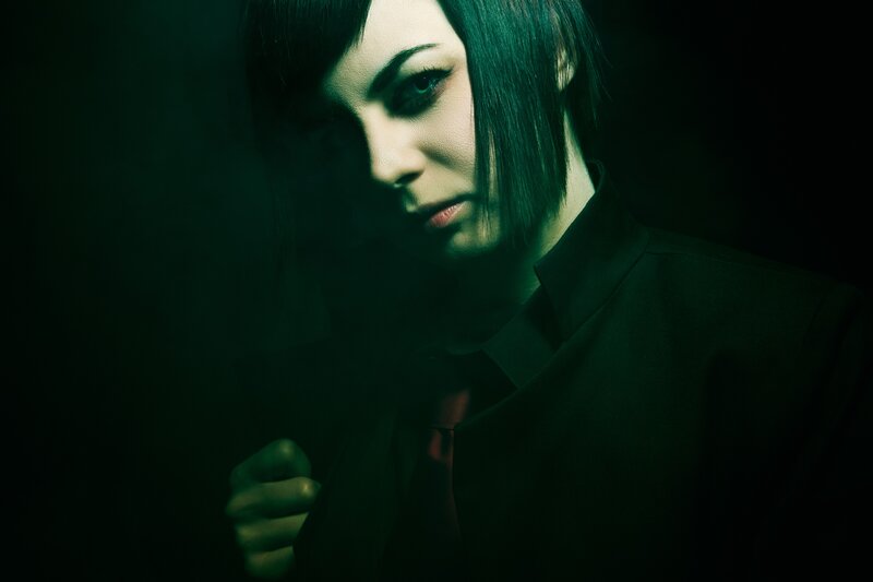 person in dark suit with green lighting