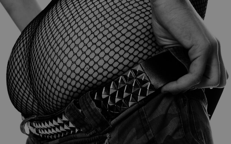 person in fishnet top and studded belt