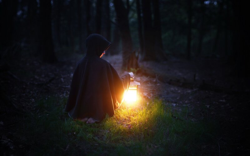 person in forest with lantern