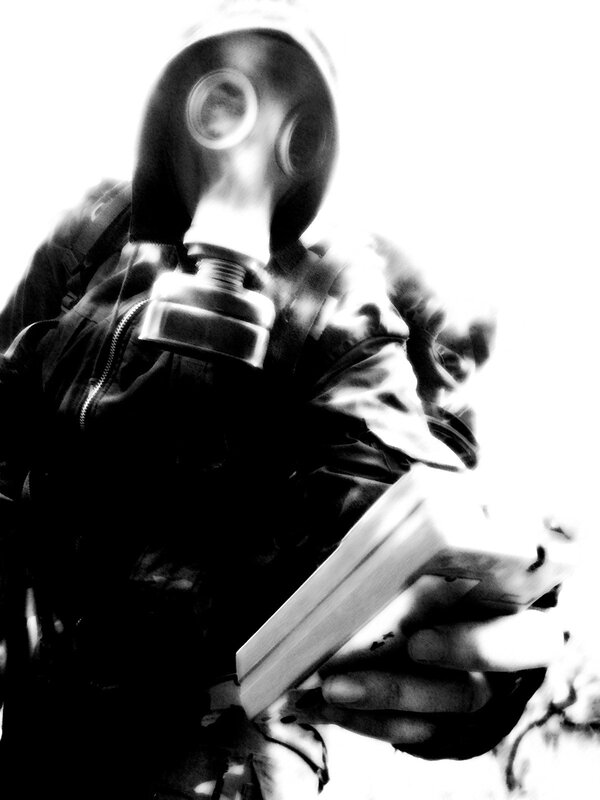 person in gas mask holding book