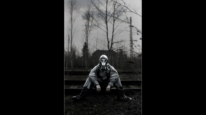 person in gas mask on train tracks