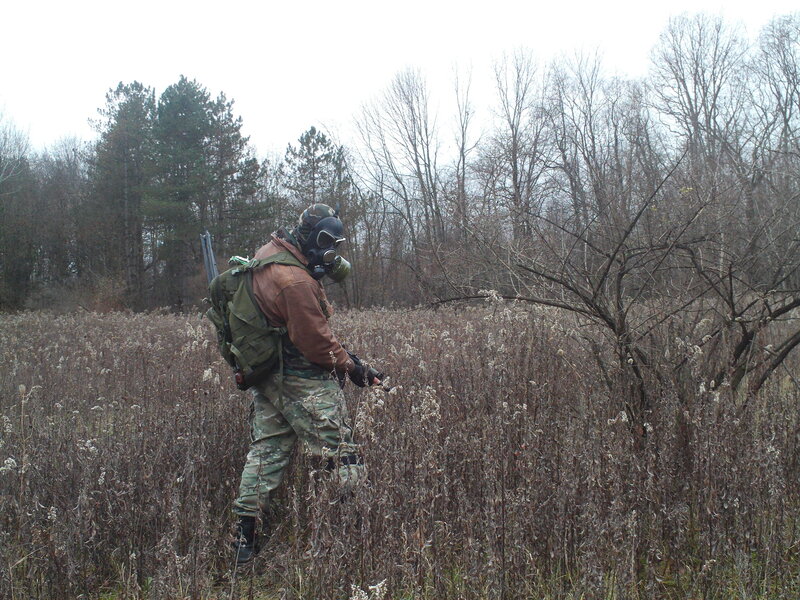 person in gas mask walking through field