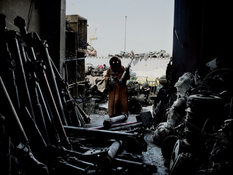 Person in hooded cloak with weapon