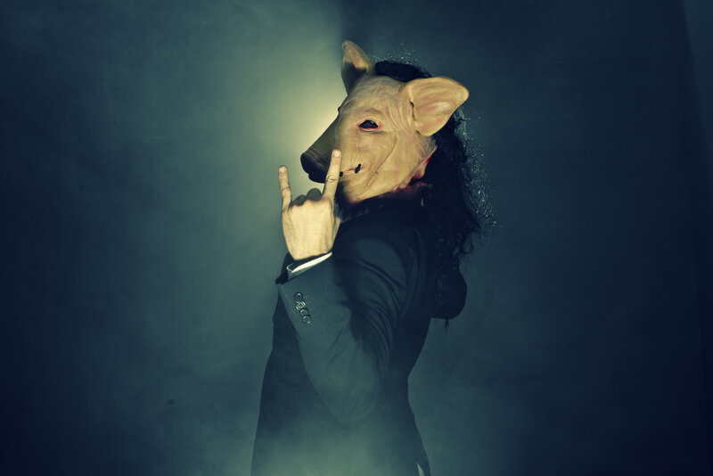 person in pig mask making rock gesture