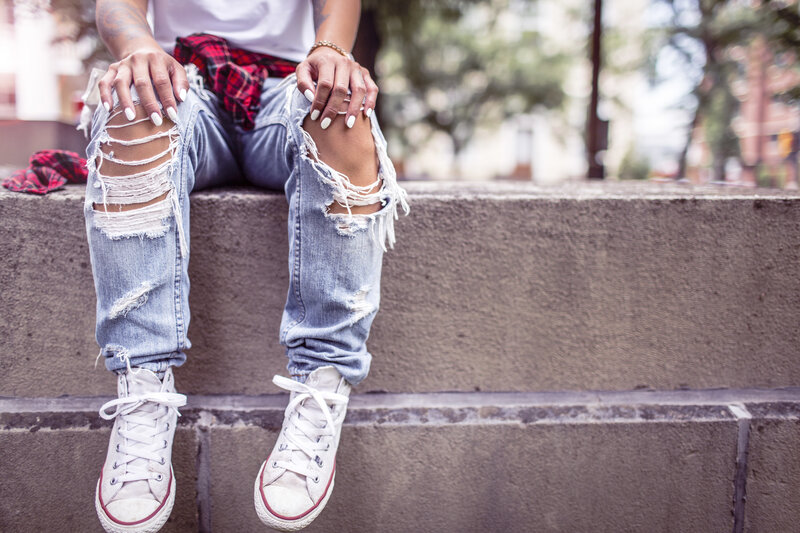 person in ripped jeans sitting