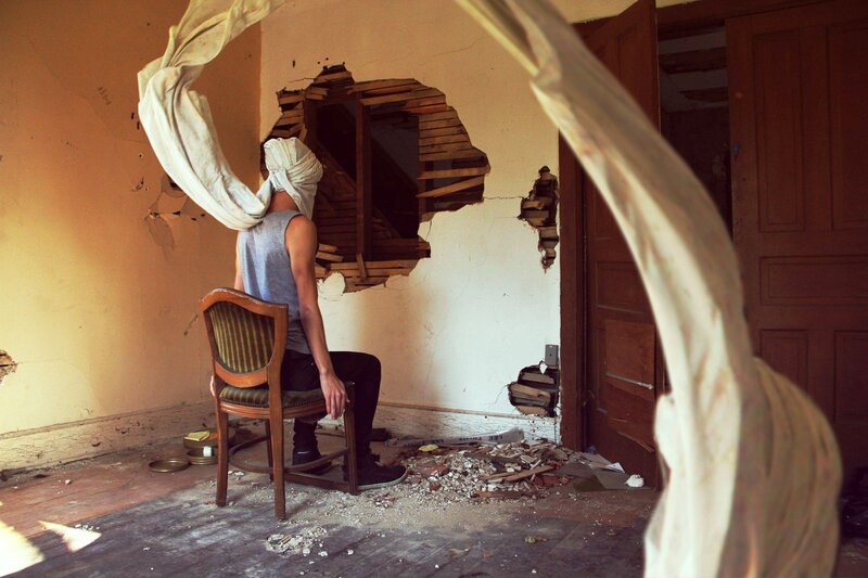 Person in ruined room with torn cloth
