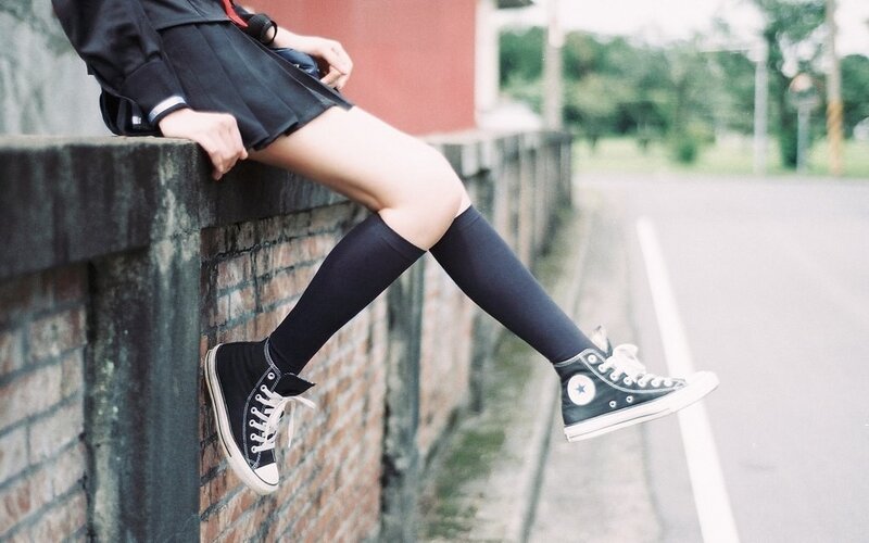 person in school uniform sitting on wall