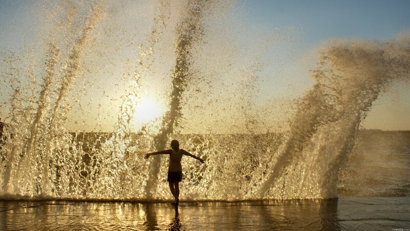 person in water spray at sunset