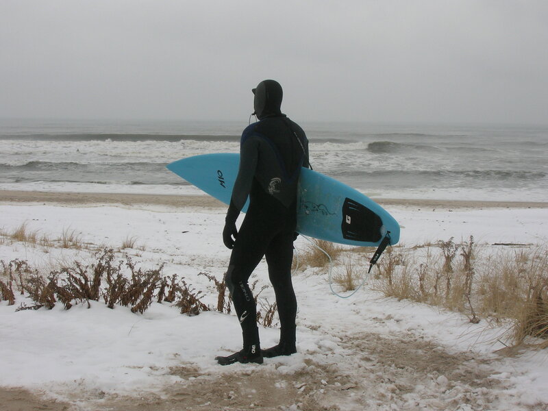 Person in Wetsuit with Surfboard