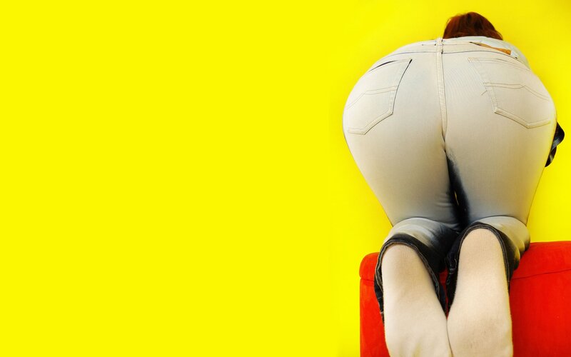 person in white jeans on red couch