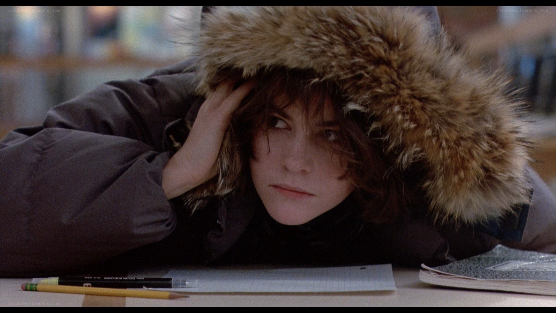 person in winter coat at desk