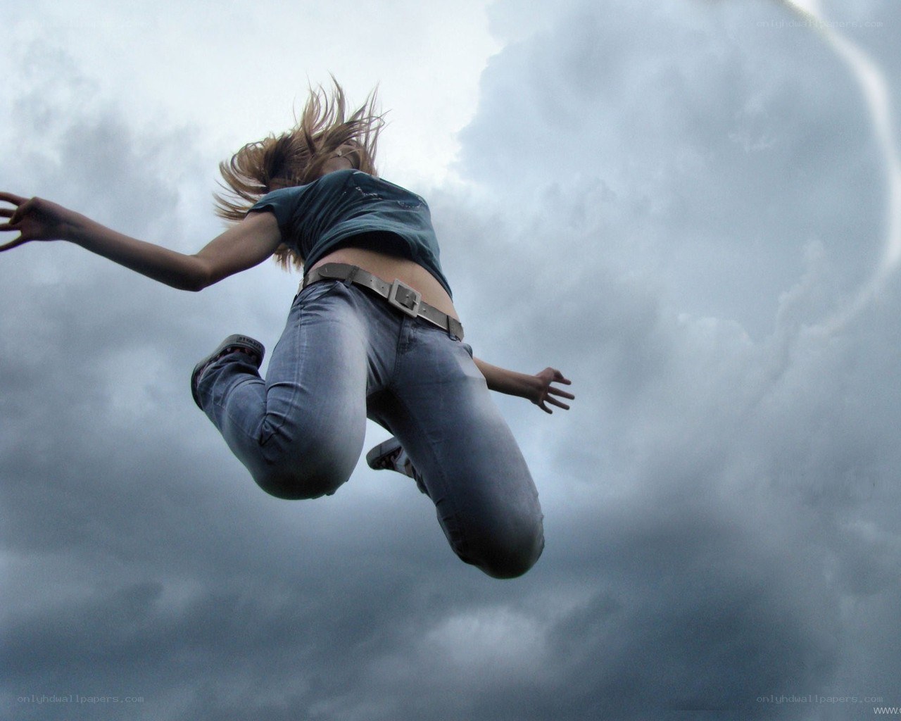 person jumping against cloudy sky