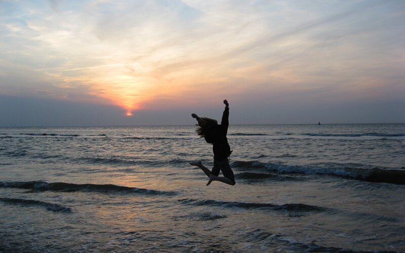 Person jumping at sunset on beach
