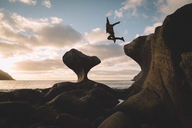 Person Jumping Between Rocks — Blue