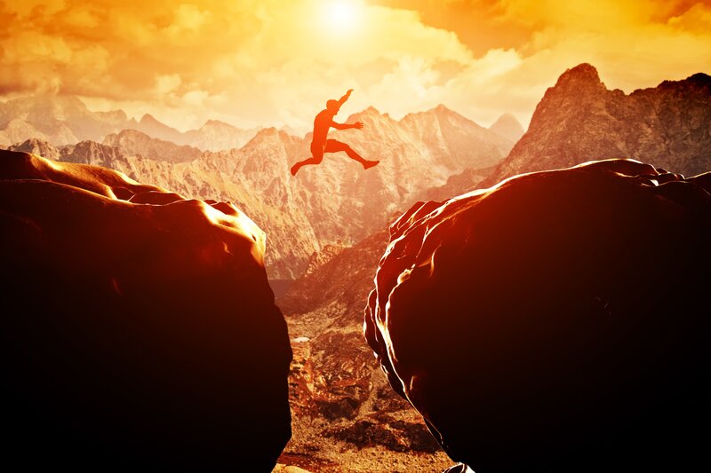 Person Jumping Between Rocks