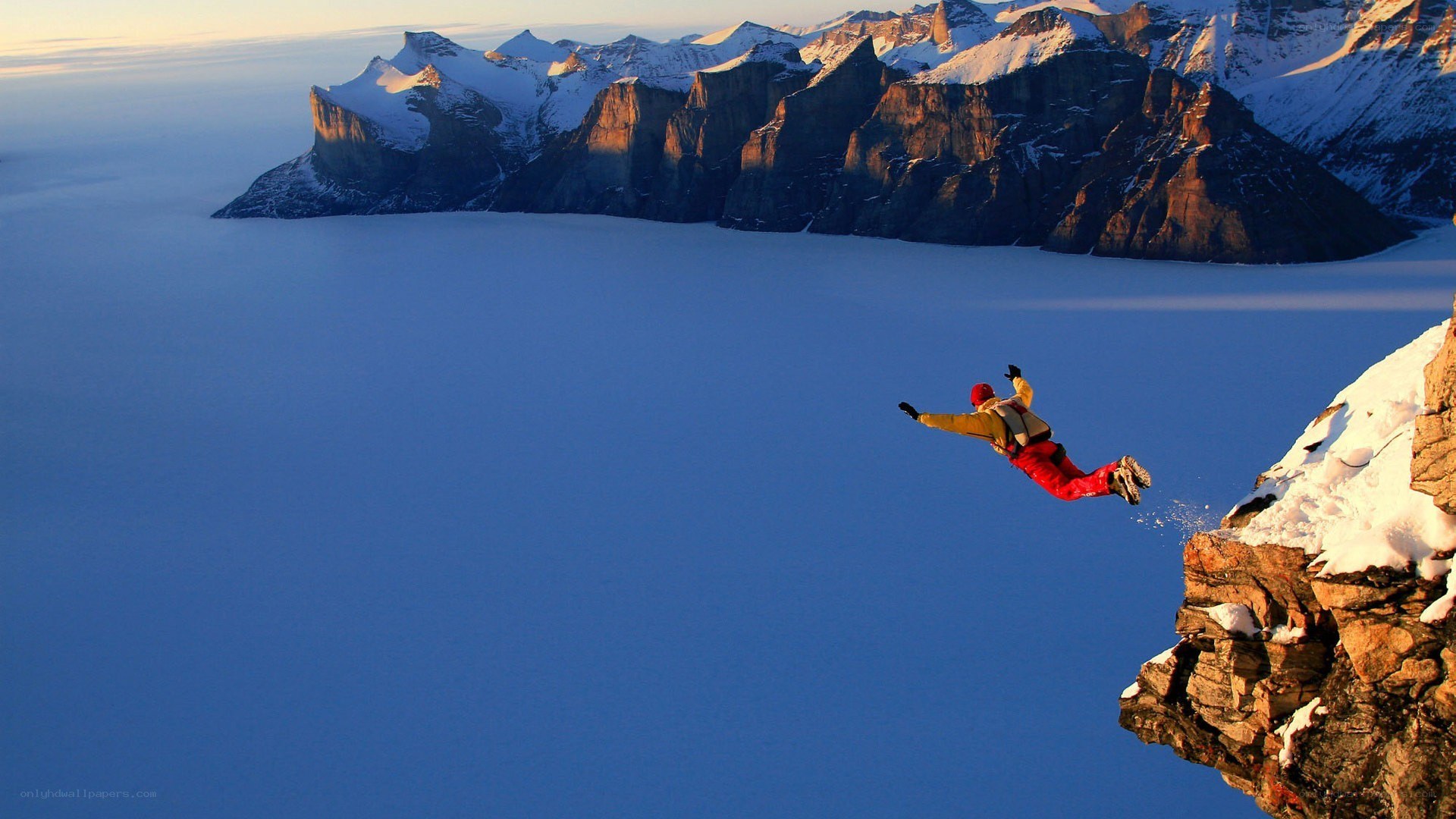 person jumping from snowy cliff
