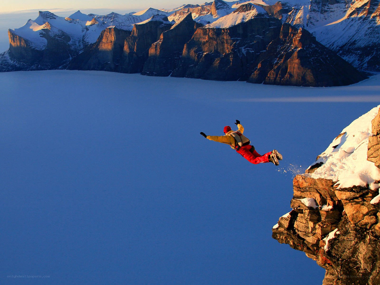 Person jumping from snowy cliff