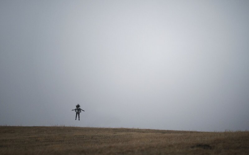 Person Jumping in Field — Gray