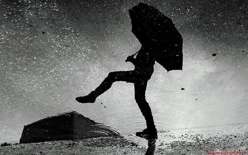 person jumping in rain with umbrella