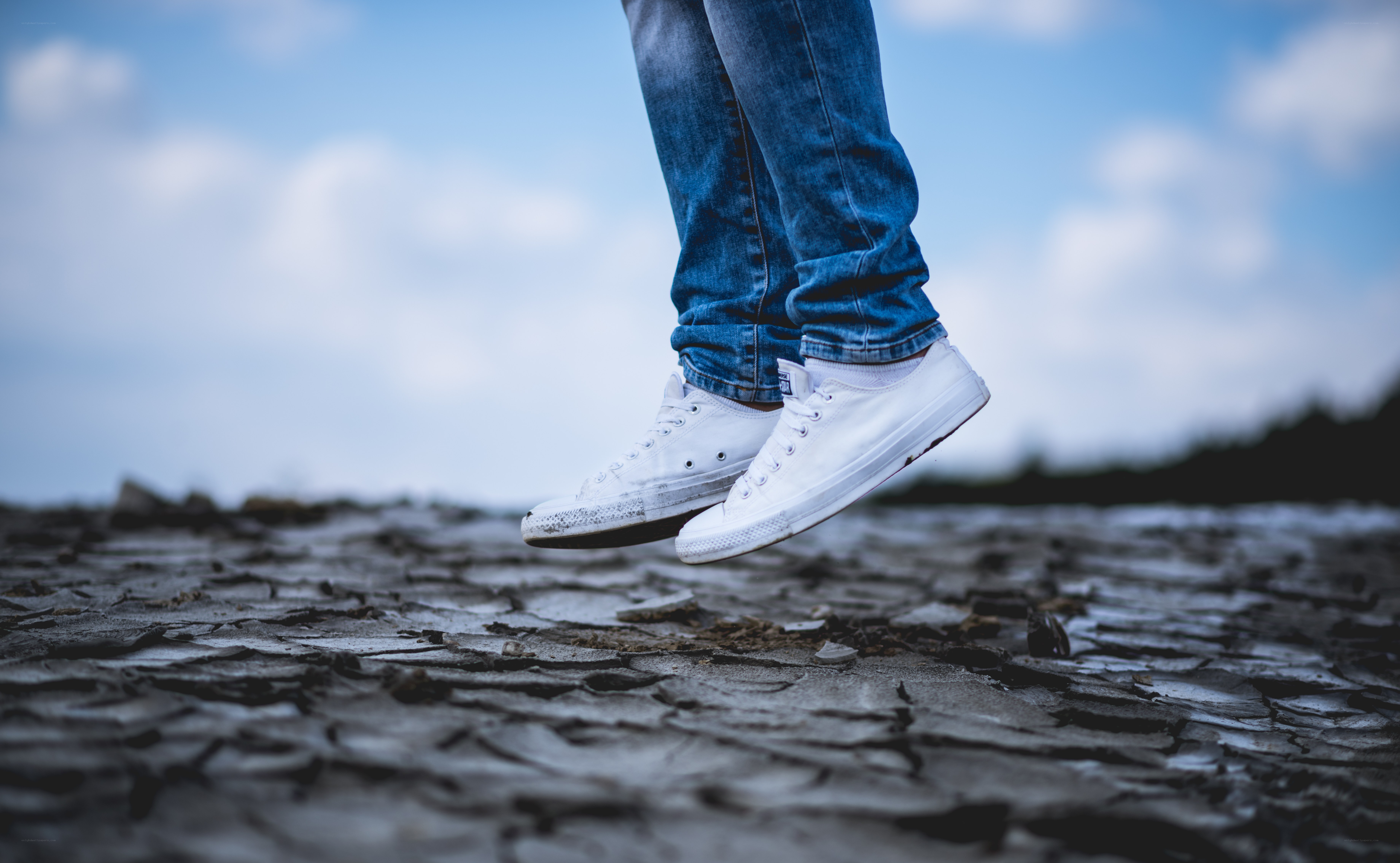 person jumping in white sneakers