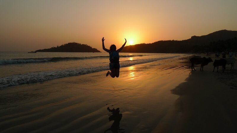 person jumping on beach at sunset