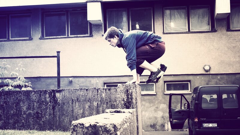 person jumping over concrete barrier