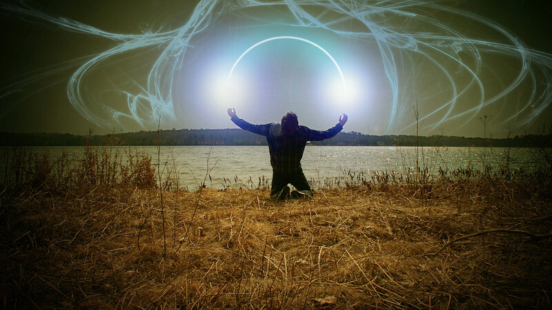 person kneeling by lake with light circle