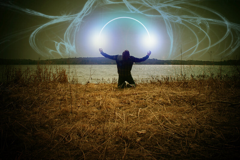 person kneeling by lake with light circle