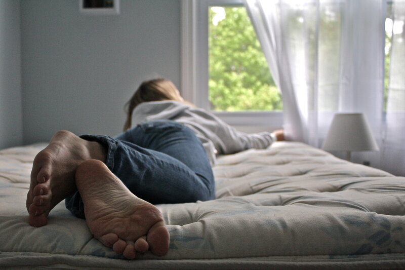 person lying on bed near window