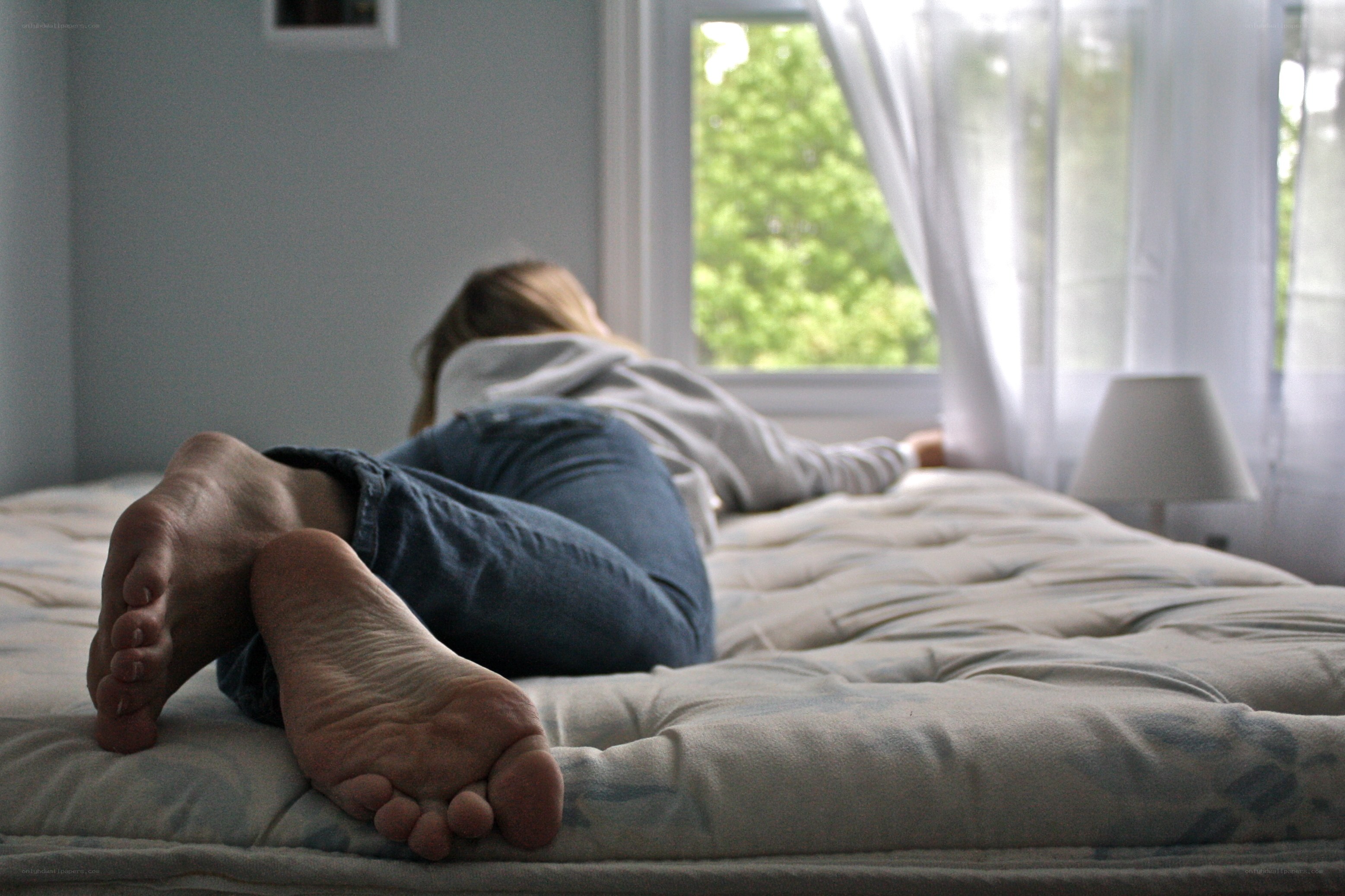 person lying on bed near window