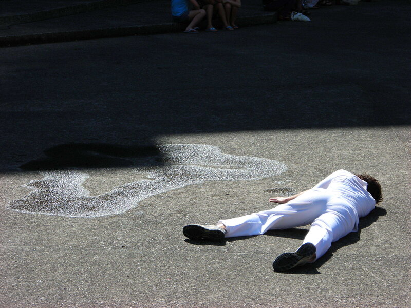 Person lying on pavement in white outfit