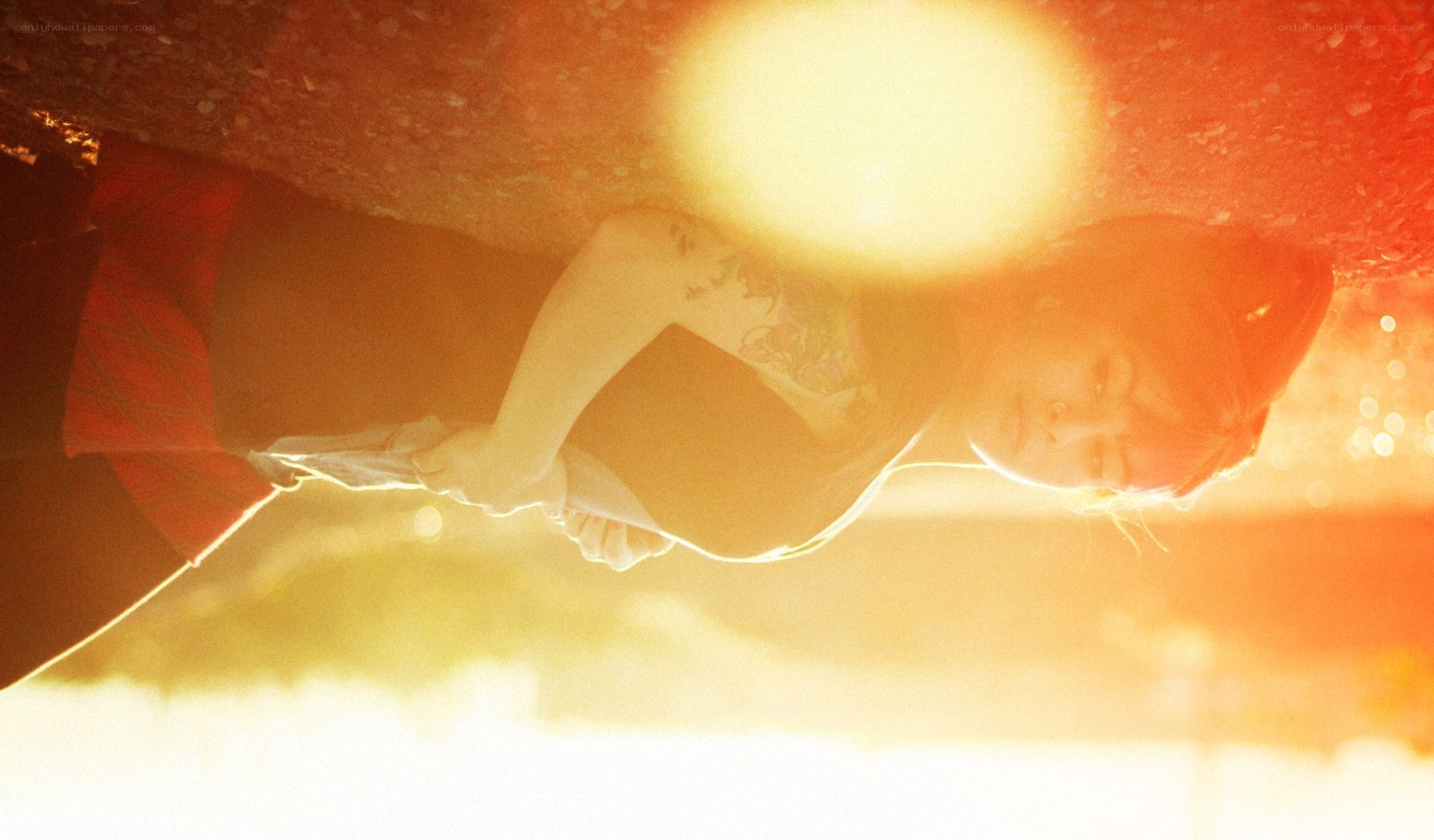 person lying under car at sunset