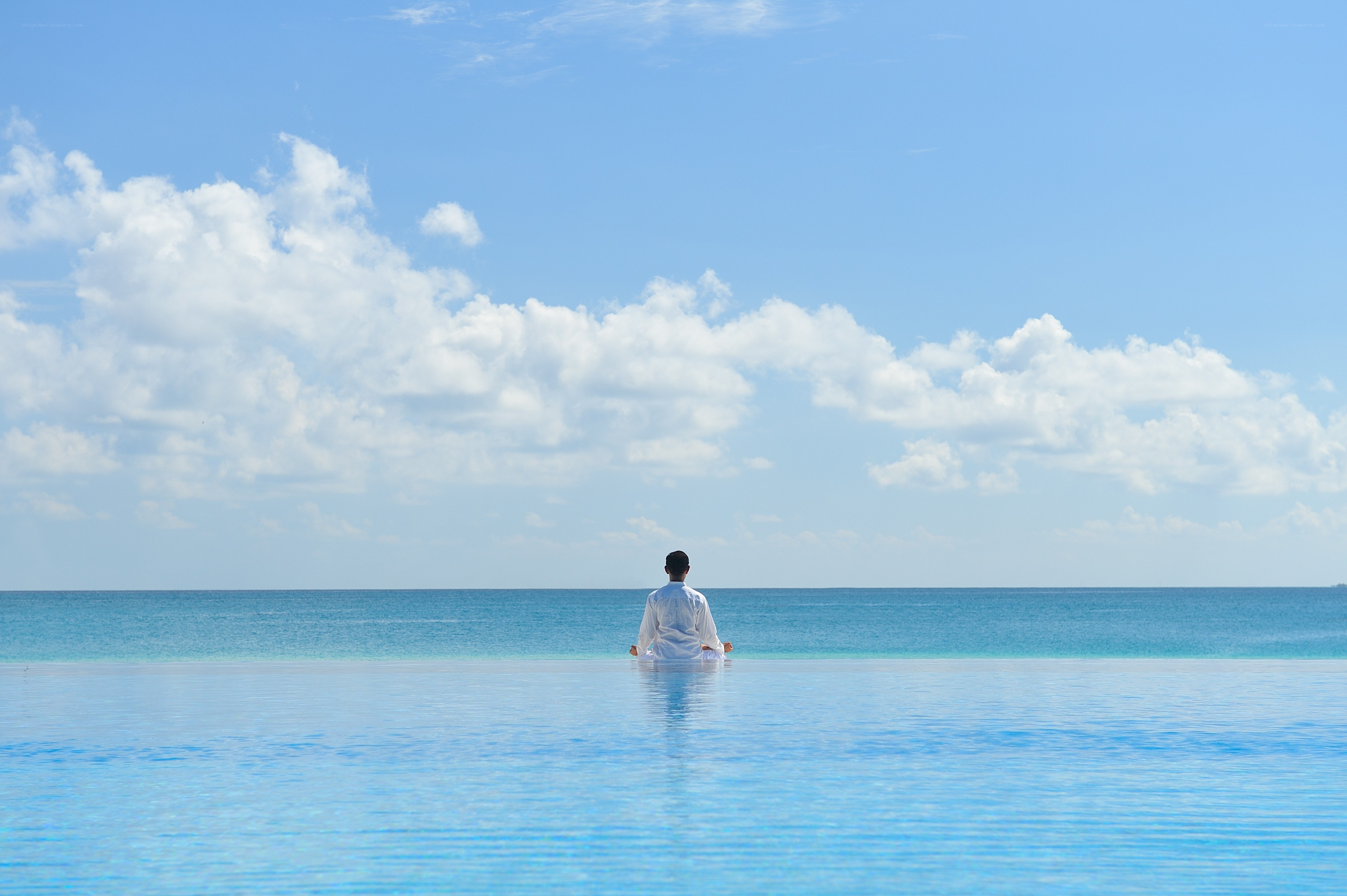 Person meditating at infinity pool