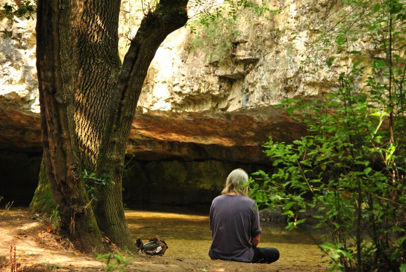 Person meditating by a stream