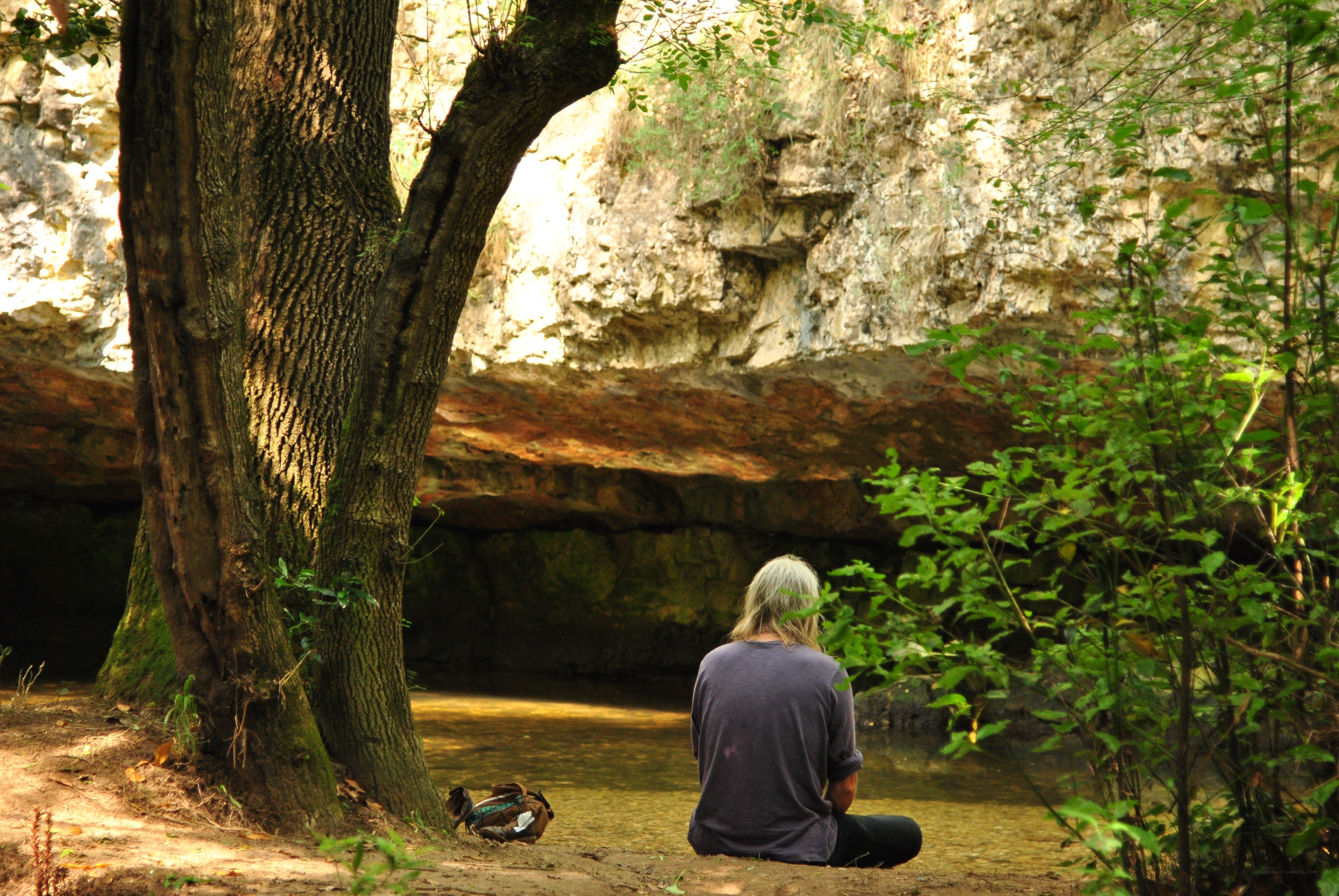 Person meditating by a stream