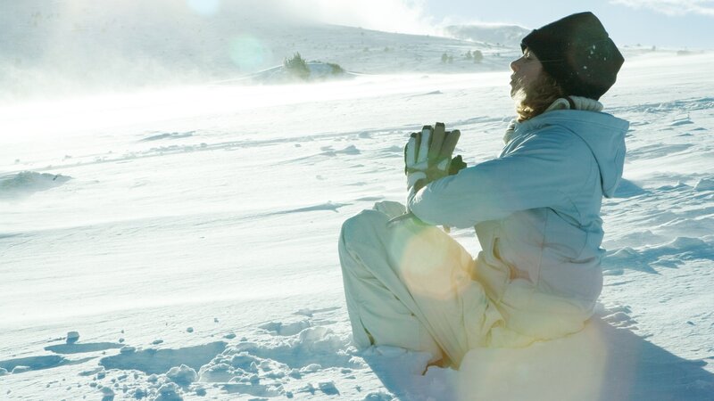 Person meditating in snowy landscape