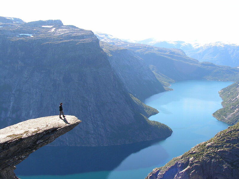 Person on a cliff overlooking a fjord
