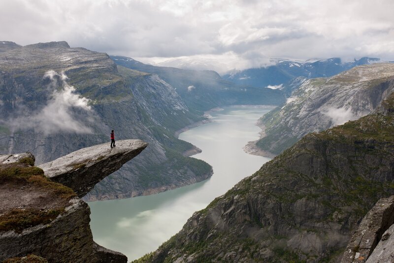 person on a cliff overlooking a fjord