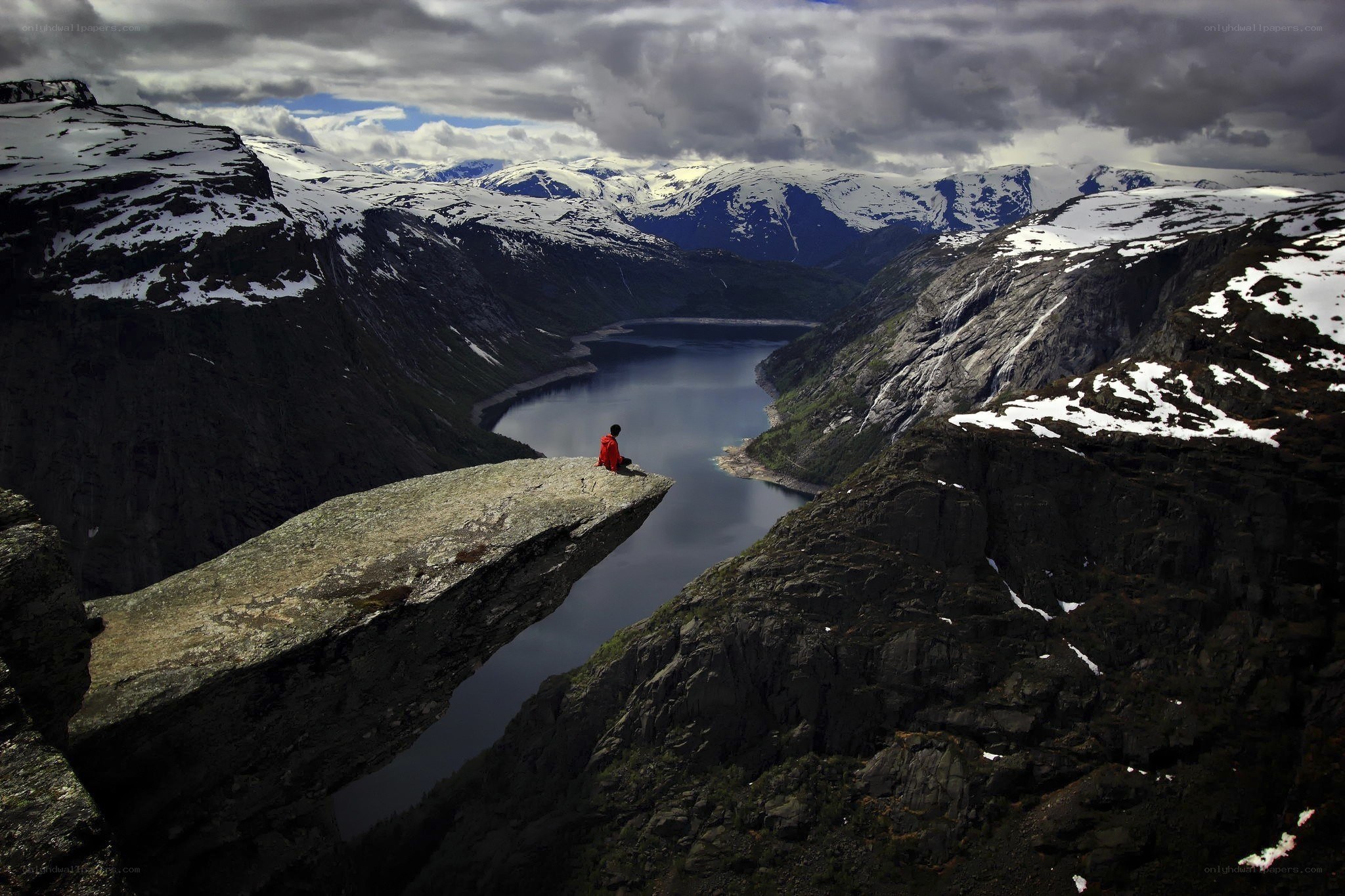 Person on a cliff overlooking a fjord
